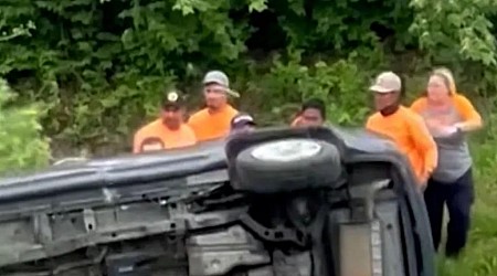 Good samaritans band together to overturn a flipped car and rescue trapped woman